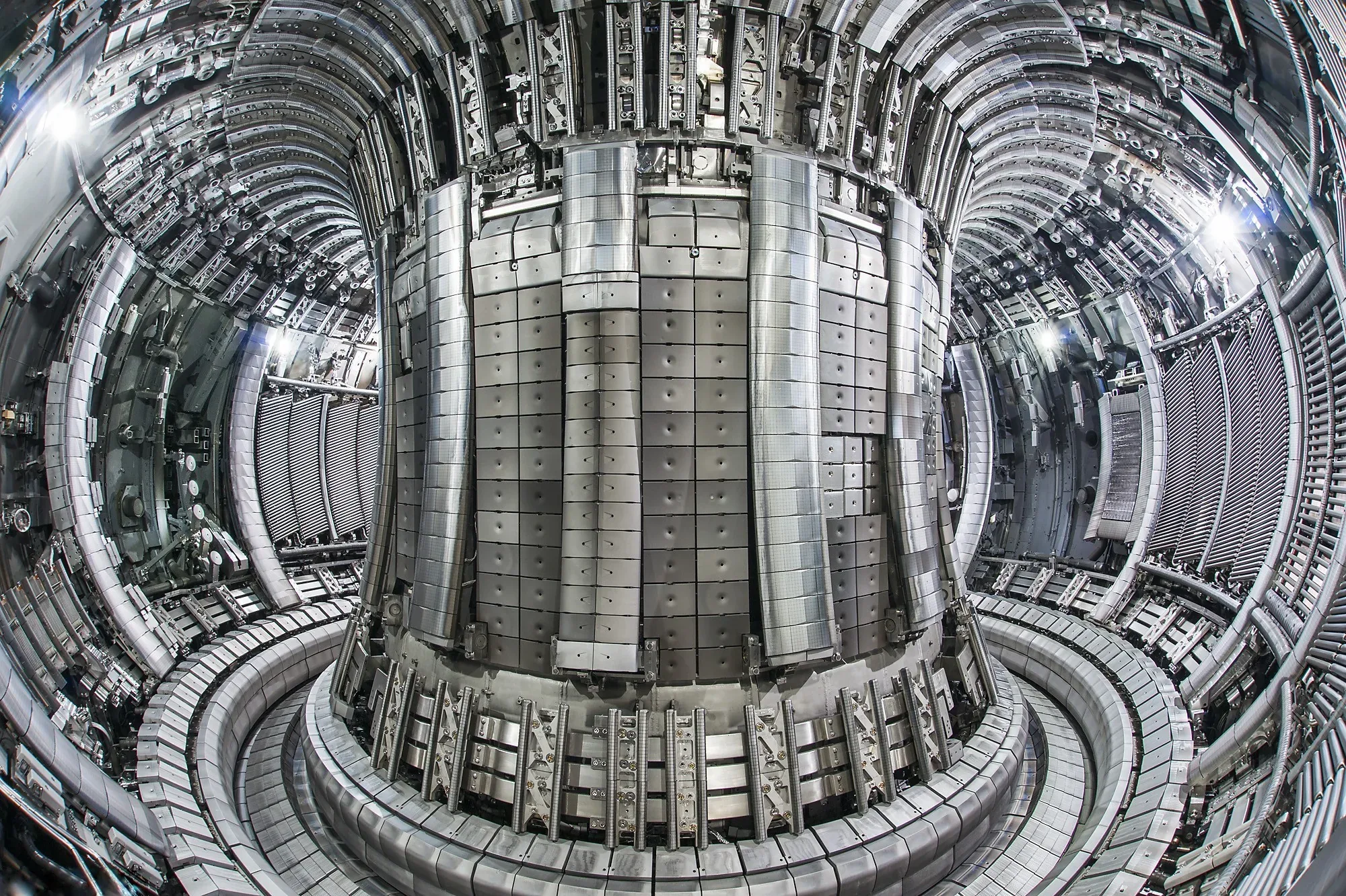 Interior of the JET fusion vacuum vessel at Culham: a ring of machined beryllium and tungsten tiles curving around the central column