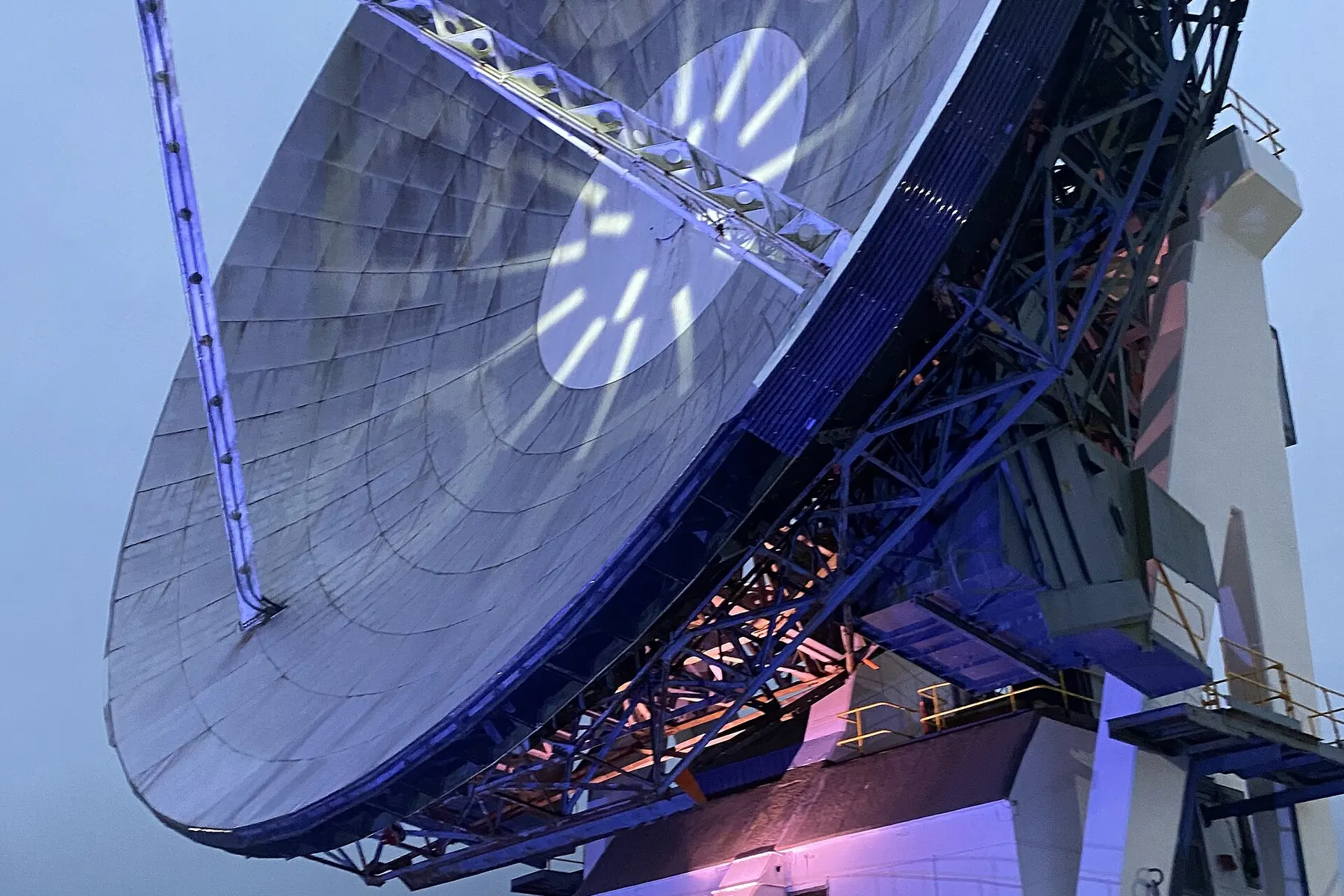 The large Arthur satellite dish at Goonhilly lit in blue and white at night