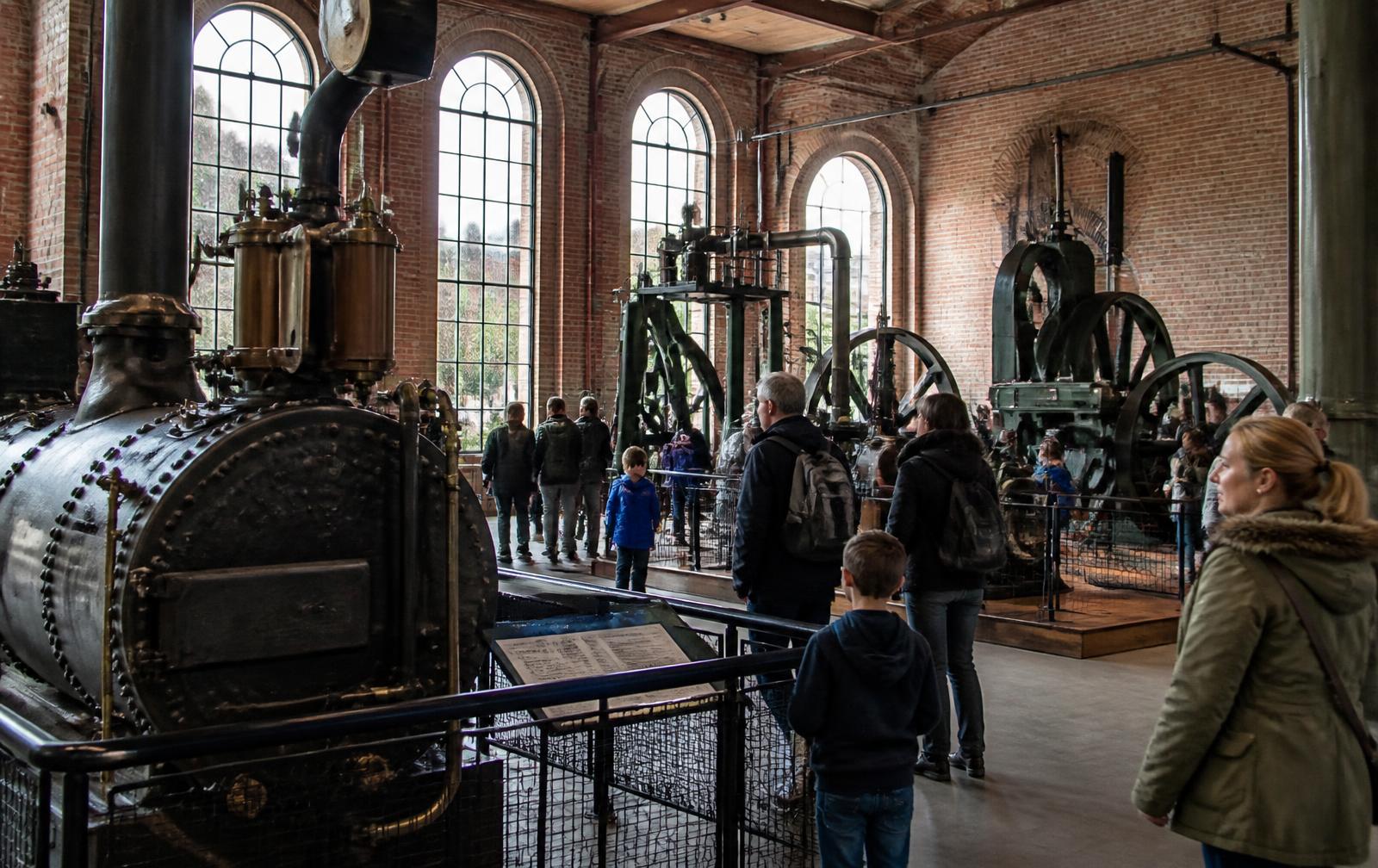 Visitors looking at historic steam engines in the brick hall of a British science and industry museum
